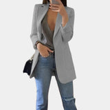 A woman wearing a gray tailored blazer in a 3XL size, styled over a dress shirt, showcasing a chic and versatile office look. The blazer features a sleek shoulder design and tailored sleeves, complemented by casual jeans, embodying a sophisticated yet relaxed style.