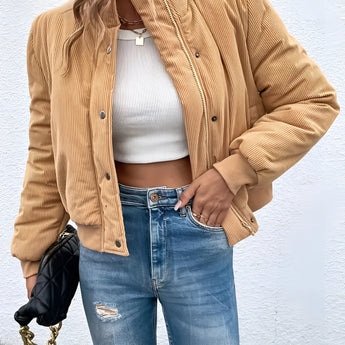 Tan corduroy bomber jacket for women displayed on a model wearing casual jeans and a dress shirt. The jacket features a trendy fall design with a relaxed fit, showcasing details like long sleeves and a high neckline. Its beige color and textured fabric make it a stylish choice for outerwear.
