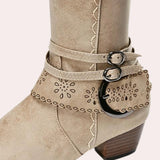 Taupe suede knee-high boots with a Western-inspired design, featuring a studded heel and a convenient side zipper.