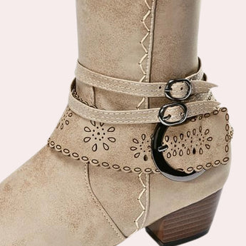 Taupe suede knee-high boots with a Western-inspired design, featuring a studded heel and a convenient side zipper.
