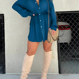 Teal oversized shirt dress paired with thigh-high suede boots, showcasing a casual chic style, worn by a model with eyewear.