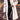 Woman wearing a long beige oversized faux fur winter coat, white XL variant, paired with stylish black shoes and fashionable eyewear.