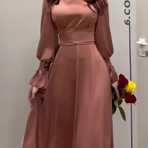Terracotta satin evening gown with elegant puff sleeves, featuring a fitted waist and a flowing skirt, designed as a sophisticated bridesmaid dress.