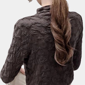 Textured black floral embossed high-collar women's top featuring a high neckline and long sleeves, showcasing intricate floral patterns against a sleek black fabric.