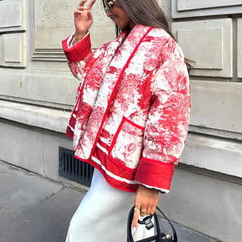 Red textured bomber jacket in stylish monochrome winter street style, worn by a person standing. The jacket features long sleeves, a high neck, and reaches the waist, offering a modern and fashionable look.