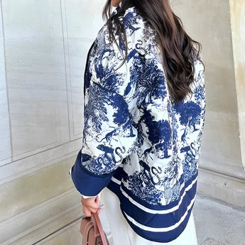 A blue textured bomber jacket in a monochrome winter street style worn by a person. The jacket features a stylish collar, long sleeves, and a comfortable fit, highlighting the waist and shoulders.