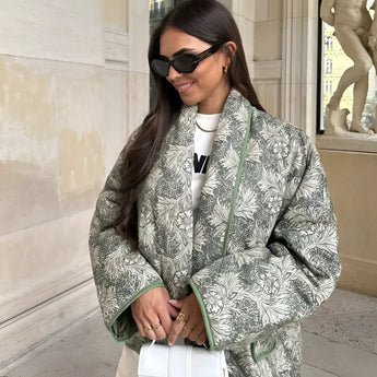 Textured bomber jacket in light green with a patterned design, worn by a person accessorized with sunglasses, showcasing a stylish monochrome winter street style.