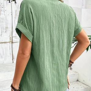 Woman wearing a textured olive green pleated blouse paired with blue jeans, showing front view with focus on shoulder, neck, and arm areas, suitable for casual summer fashion.