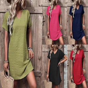 A woman modeling a textured V-neck shift dress in a casual, lightweight style suitable for summer. The dress is a mini-length and features a chic purple color. The model has a fashionable hairstyle, and the photograph highlights her shoulder and leg, emphasizing the dress's fit and style.