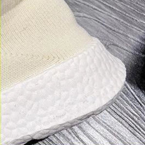 Textured white sneakers on a hardwood floor, showcasing their eco-friendly design, lightweight structure, and breathable material.