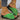Green women's flat sandals with a bow-tie design suitable for beachwear, featuring a trendy, fashion-forward style.