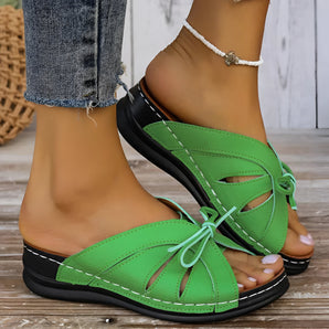 Green women's flat sandals with a bow-tie design suitable for beachwear, featuring a trendy, fashion-forward style.