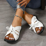 Trendy green women's flat sandals featuring a bow-tie design, worn on a woman's foot against a blue background, showcasing a fashionable beachwear style.