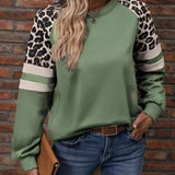 Women's streetwear top with a trendy leopard print sleeve and green pullover design, paired with jeans, showcasing a fashionable look.