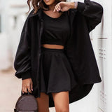Smiling woman wearing a black XL hoodie dress with trendy cut-out shoulders, showcasing streetwear style. The dress features long sleeves and a comfortable fit, highlighting the waist and thigh area.