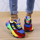 Multicolor sneakers with a rainbow sole, featuring vibrant colors like yellow, red, electric blue, and magenta, worn on a human leg. The main body of the shoe is white, highlighting the colorful sole design.