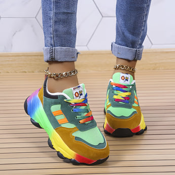 Multicolor sneakers with a vibrant rainbow sole on a person wearing blue denim jeans.