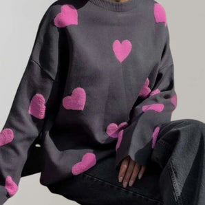 Trendy women's cozy pullover featuring a grey and pink heart pattern, shown in black-pink colorway and size large, with long sleeves and a comfortable fit.