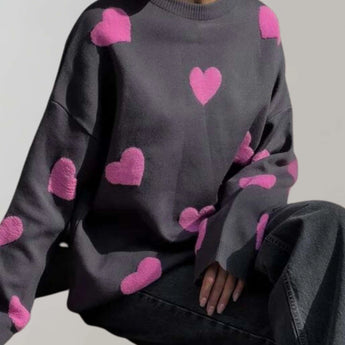 Trendy women's cozy pullover featuring a grey and pink heart pattern, shown in black-pink colorway and size large, with long sleeves and a comfortable fit.