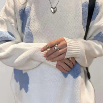 Trendy women's cozy pullover featuring a grey and pink heart pattern with long sleeves, displayed on a mannequin with a focus on the shoulder and arm area, showcasing the design and fit.