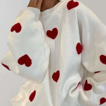 Trendy women's cozy pullover in white with grey and pink heart pattern, featuring long sleeves and a comfortable collar.
