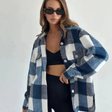 Trendy women's oversized plaid jacket in grey, featuring a collared neckline and long sleeves, styled for chic autumn streetwear. The model wears sunglasses, accentuating the fashionable outerwear look.