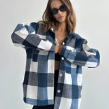 
A stylish woman wearing a trendy oversized plaid jacket in blue, ideal for chic autumn streetwear. The jacket features long sleeves and broad shoulders, paired with sunglasses for a fashionable look.