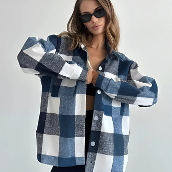 
A stylish woman wearing a trendy oversized plaid jacket in blue, ideal for chic autumn streetwear. The jacket features long sleeves and broad shoulders, paired with sunglasses for a fashionable look.