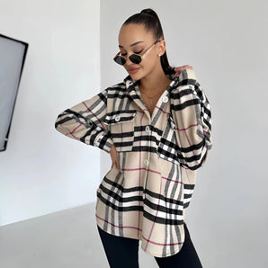 Oversized plaid jacket worn by a woman featuring a chic tartan pattern, with long sleeves, and styled as trendy autumn streetwear. The woman is wearing sunglasses and making a casual gesture, highlighting the jacket's relaxed fit around the shoulders and waist.