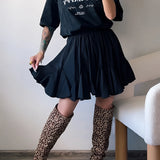 Trendy women's urban chic outfit featuring a black tee, pleated skirt, and leopard print boots.