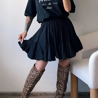 Trendy women's urban chic outfit featuring a black tee, pleated skirt, and leopard print boots.