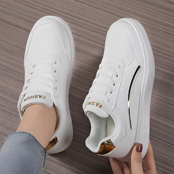 Trendy women's white low-top sneakers with gold accents showcasing a stylish design, suitable for outdoor activities and sportswear.