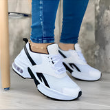 Women's white sneakers with bold soles worn by a person, showcasing a modern and stylish design.