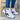 Women's white sneakers with bold soles worn by a person, showcasing a modern and stylish design.
