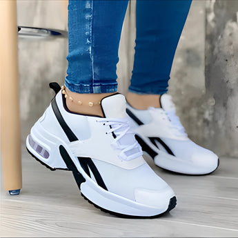 Women's white sneakers with bold soles worn by a person, showcasing a modern and stylish design.