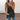 A black V-neck tank top with a zipper front, worn by a woman in a casual summer setting. The tank top is sleeveless and designed for a size 2XL.