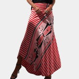 
A woman wearing a bohemian maxi skirt with tribal print, featuring yellow stripes, in a wrap style. The skirt is paired with a rose-colored top, in size XL.