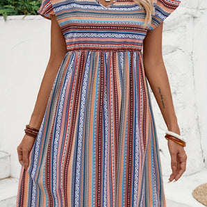 A woman wearing a boho chic summer dress featuring a tribal print, V-neckline, and A-line midi silhouette.