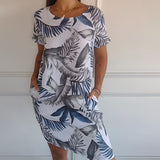 
A woman wearing a white tropical botanical print sleeveless summer shift dress, perfect for beachwear, in size 3XL. The dress features a relaxed fit with a round neckline and falls above the knee.