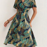 Tropical Leaf V-Neck Mini Dress in green, size XL, featuring a bohemian summer resort style. The dress showcases a sheath silhouette with a one-piece garment design, highlighting the shoulders and arms.