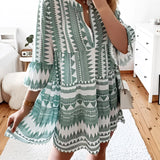 Tropical Print Button-Up Mini Dress in light green with pink accents, modeled by a person wearing the dress. The dress features short sleeves and a mini length, highlighting a vibrant summer style. The model's arms and legs are visible, emphasizing the dress's fit and style.