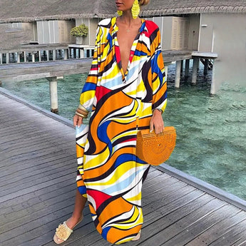 Luxurious tropical print kaftan in green and white, featuring long sleeves and a flowing design, perfect for leisure and travel. The kaftan is styled with sunglasses, embodying a fashionable beachwear look against a backdrop of water and buildings.