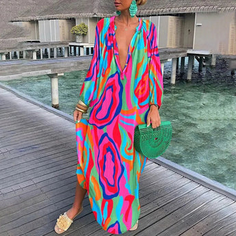 
A luxury beachwear kaftan featuring a tropical print in green and white, with long sleeves and a relaxed fit, shown in a Rose color variation in size 2XL. The kaftan is styled in a leisurely setting, emphasizing fashion design elements.