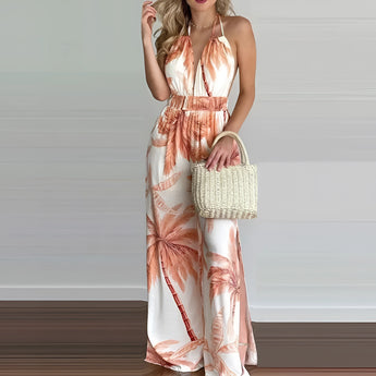 A model wearing a tropical print halter maxi dress suitable for beach weddings and resort wear, accessorized with sunglasses and a bag, highlighting the dress's flowing design that fits comfortably around the waist and falls elegantly to the thighs and knees.