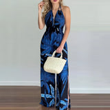 Blue tropical print halter maxi dress in 2XL size, featuring a relaxed fit suitable for beach weddings or resort wear, shown with a model accessorizing with a shoulder bag and sunglasses.