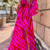 Tropical print maxi dress in pink and red with a flowy design, featuring a high slit and vibrant patterns. The dress is shown in a 2XL size, emphasizing shoulder and waist details.