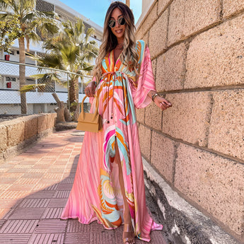 Tropical print maxi dress in light pink, featuring a flowy design perfect for resort wear, with a high slit for added elegance.