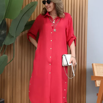 Turquoise linen summer dress with asymmetrical hem and long sleeves, displayed on a mannequin standing outdoors.