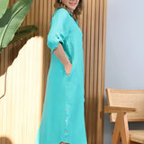 Turquoise linen asymmetrical hem long sleeve summer dress with a focus on the shoulder and sleeve design, displayed in a natural outdoor setting.