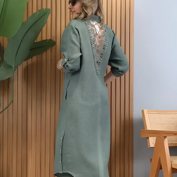 Turquoise linen summer dress with an asymmetrical hem, featuring long sleeves and a round neckline. The dress has a fitted waist and reaches the knee, showcasing a fashionable design.